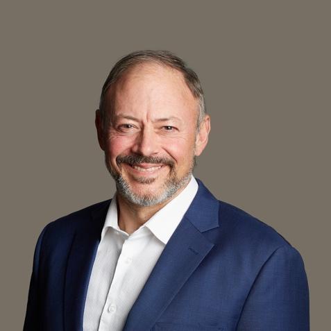 James Tate, Director at JES, smiling, wearing a navy suit jacket and white open-collar shirt